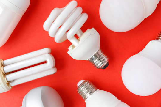Spent incandescent halogen, cfi fluorescent, led, lumens light and energy saving bulbs tube, red background. Lamps containing mercury - extremely hazardous waste, very toxic to human health. Close up.