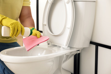 Man cleaning toilet bowl in bathroom, closeup