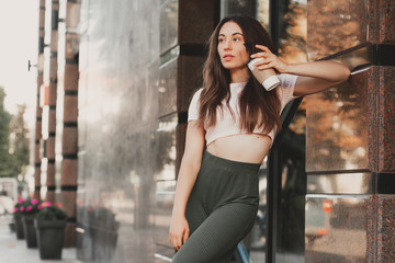 Fototapeta premium Beautiful smiling woman drink coffee walking on the city in summer day.