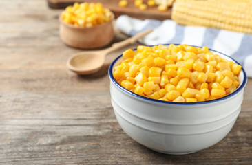 Delicious canned corn in bowl on wooden table, closeup. Space for text