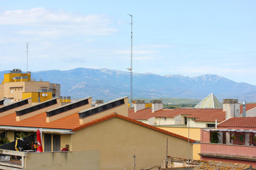 Fototapeta premium Tile roofs of houses on a background of snow-covered mountains, Europe, Spain.