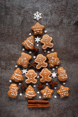 Gingerbread, anise stars and cinnamon sticks create a Christmas tree on a dark stone background. The concept of decorating food. Flat lay