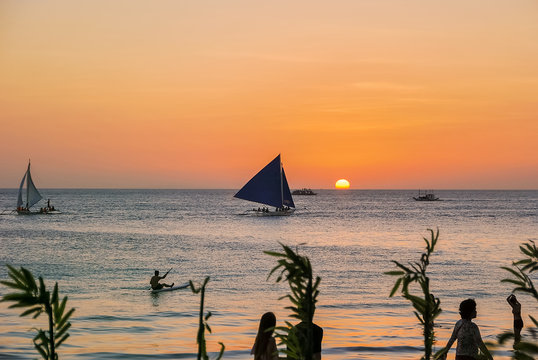Beautiful sunset over bay at Sabang Puerto Galera of Oriental Mindoro, Philippines near Isla Verde Passage and Manila. Sunset Silhouettes. Amazing tropical sunset. Seascape during sunset. People swim