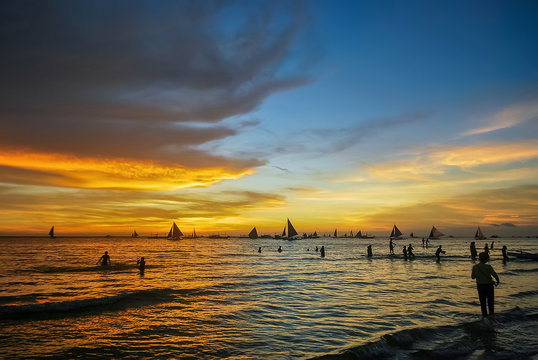 Beautiful sunset over bay at Sabang Puerto Galera of Oriental Mindoro, Philippines near Isla Verde Passage and Manila. Sunset Silhouettes. Amazing tropical sunset. Seascape during sunset. People swim