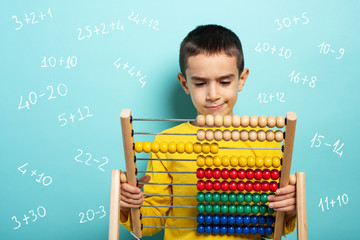 Child tries to solve mathematical problem with abacus. Cyan background