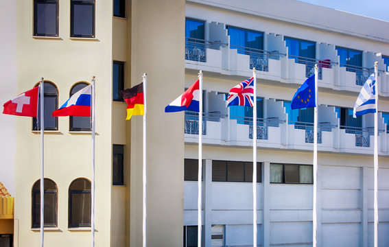 Switzerland, Russian, Netherlands, German, British, Greek, European Union Flags on flagpoles fluttering in the wind opposite the hotel