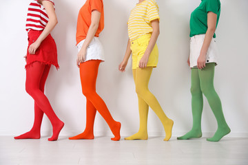 Women wearing bright tights near white wall, closeup