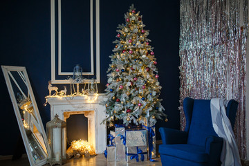 Decorated for The new year Interior of the house. Christmas tree and decorated Studio, garlands of lights, decorations, gift boxes in a cozy home, a large armchair and a fireplace.
