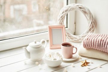 Christmas decor, balls, woolen plaid on the window background, home comfort concept, seasonal winter celebrations. Postcard Template. Christmas pink cup with marshmallow.