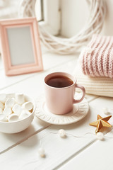 Christmas decor, balls, woolen plaid on the window background, home comfort concept, seasonal winter celebrations. Postcard Template. Christmas pink cup with marshmallow.