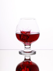 Red alcohol cocktail in glass with splash on white background, selective focus on the liquid jet