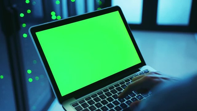 Database worker using green laptop mock-up for diagnostics, running backup programs in server cabinet, deactivating modern data center with one click. Close-up. Smart technology.