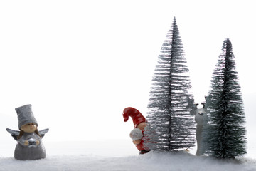 Stillleben mit Weihnachtswichtel, Elch und Christkind in einer Winterlandschaft mit Nadelbäumen