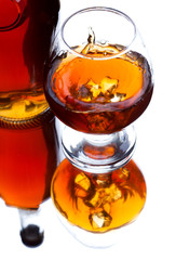 Glass and bottle of whiskey with splash on light background, selective focus on the glass