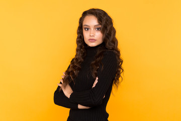 Fototapeta premium Portrait of woman in trendy black clothes standing isolated in the yellow studio