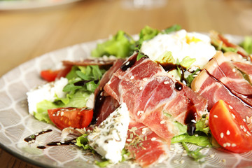 Delicious prosciutto salad with vegetables on plate, closeup