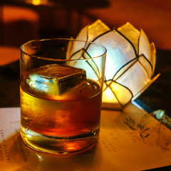 Glass of whiskey on a black wooden table in a bar