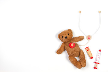 Teddy bear with toy stethoscope and toy medicine tools on a white background. Top view. Copy space for text