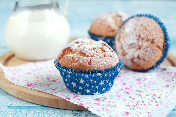 Close-up of three homemade orange muffins with a jug of milk, selective focus