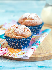 Close-up of two homemade orange muffins with a jug of milk, selective focus