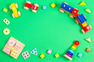 Baby kids toys background. Wooden educational geometric stacking blocks toy, wooden train, cars, stacking pyramid tower and colorful blocks on green background