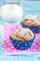 Close-up of two homemade orange muffins with a jug of milk, selective focus