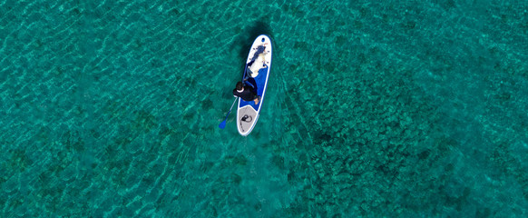 Aerial drone ultra wide panoramic photo of unidentified fit man paddling with his cute dog on a SUP...