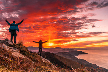 Obraz premium A couple in the incredible orange sunset on the winged Mount Jaizkibel of San Sebastian. Basque Country
