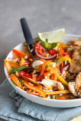 Buddha bowl lunch with grilled chicken and carrot, red bell pepper, onion, rice and herbs on light grey stone background. Healthy balanced eating. Comfort food.