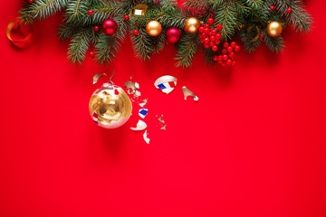 Obraz premium Christmas red background with broken glass Christmas ball and fir branches. Christmas card.