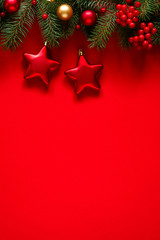 Fir branches and holiday decorations on a red background, top view with space for text. Christmas winter background, Christmas card.	