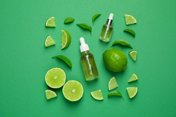 Flat lay composition with lime essential oil on green background