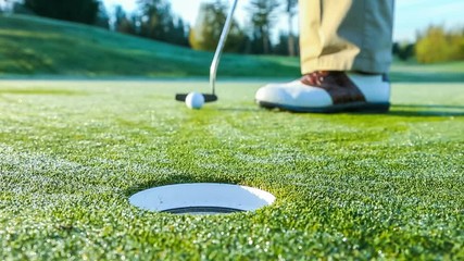 Golfer on putting green sinking a short putt - Powered by Adobe