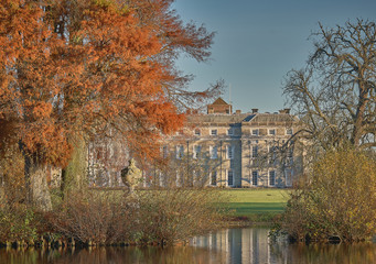 Fototapeta na wymiar Petworth House and lake with golden autumn trees