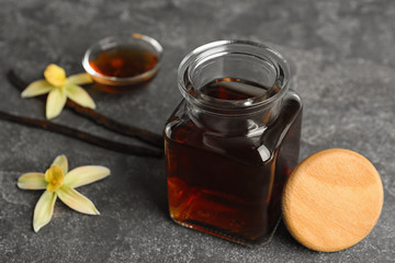 Aromatic homemade vanilla extract on grey table, closeup