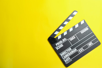 Fototapeta na wymiar Clapper board on yellow background, top view with space for text. Cinema production