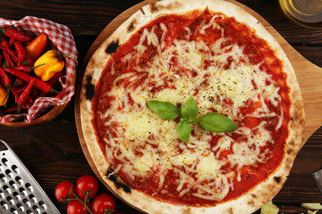 Pizza with tomatoes, mozzarella cheese, basil. Delicious italian pizza on wooden pizza board.
