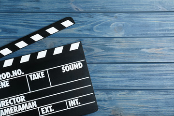 Clapper board on blue wooden background, top view with space for text. Cinema production