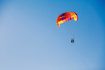 Couple under parachute hanging mid air. Having fun. Tropical Paradise. Positive human emotions, feelings, family, travel, vacation. Tourism day. Copy space