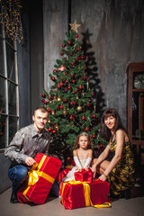Obraz na płótnie Canvas family mom dad and daughter at the Christmas tree with gifts