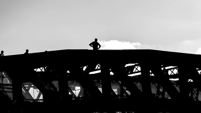 Risky behavior, young people walk and take pictures of each other on top of an old steel bridge,  time lapse