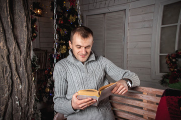 a man reading a book sitting on a swing