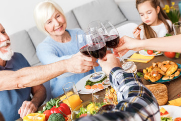Family smiling, sitting at home and clinking beverage glasses