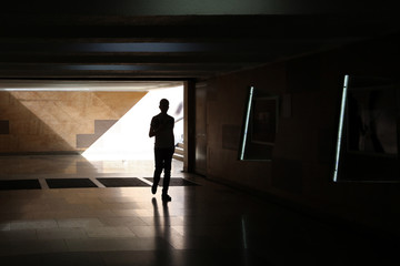 Silhouette of a man in an underground pedestrian crossing.