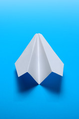 Airplane made of white paper on a blue background.