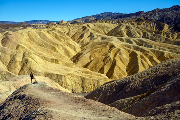 Attractive blonde woman standing in the landscape at Zabriskie Point, Death Valley National Park, California, USA