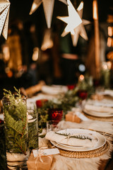 Christmas table setting for traditional lunch or dinner on a rustic table with seasonal greeting cards, tableclothes, tableware and festive decorations. Concept of family traditions and celebrations
