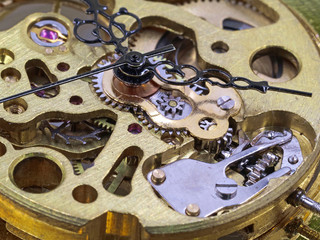 close up frontside of clockwork mechanism of a golden pocket watch