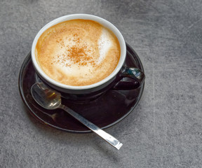 hot Italian cappuccino black cup on grey table background