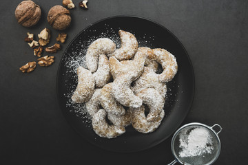 Homemade cookies with nuts, on plate over dark background. Top view.